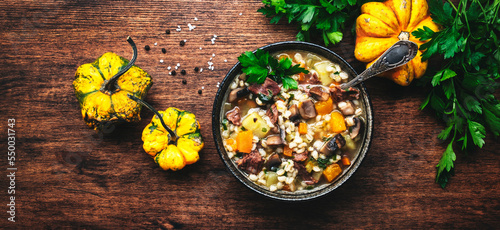 Autumn food. Warming soup with pumpkin, mushrooms, vegetables, beef and barley. Rustic wood table background, top view banner