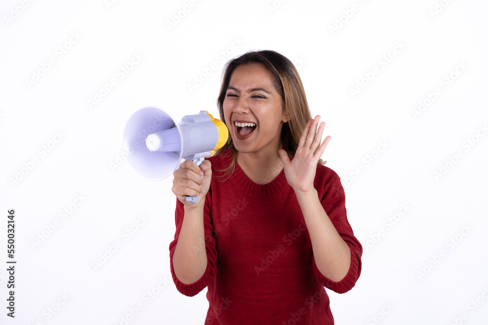 Young asian woman shouts into a megaphone. Isolated white background. Young asian woman shouts into a megaphone. Isolated white background.