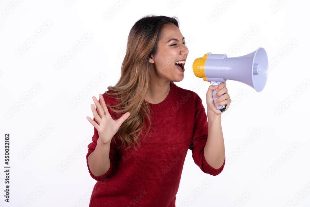 Young asian woman shouts into a megaphone. Isolated white background. Young asian woman shouts into a megaphone. Isolated white background.