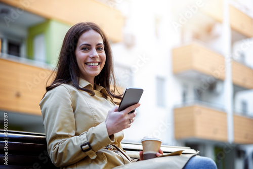Woman sitting on bench and using smart phone