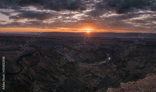 Dramatischer Sonnenuntergang - Blick auf eine Schleife des Fish Rivers bei Sonnenuntergang, wie er sich durch den Fish River Canyon windet (Namibia)