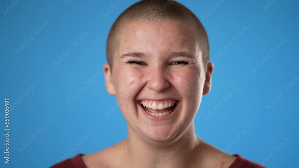 Closeup slow motion of laughing smiling young gender fluid woman 20s years old posing isolated on blue chroma key background studio. Portrait sincere emotions lifestyle concept Closeup slow motion of laughing smiling young gender fluid woman 20s years old posing isolated on blue chroma key background studio. Portrait sincere emotions lifestyle concept