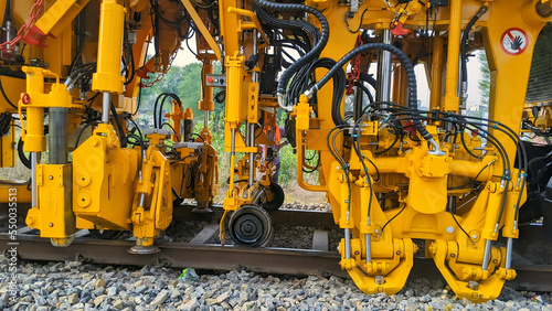 Plasser India or also called Tamping Machine functions to compact the stones under the rail tracks bearings. Yellow railway Motor Grader machine on working. photo
