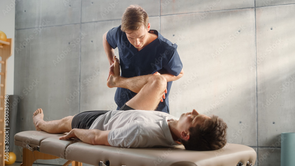 Advanced Sport Physiotherapy Specialist Stretching and Working on Muscle Groups or Joints with Young Male Athlete. Fit Sportsman Recovering from Mild Injury, Undergoing Rehabilitation. - obrazy, fototapety, plakaty 