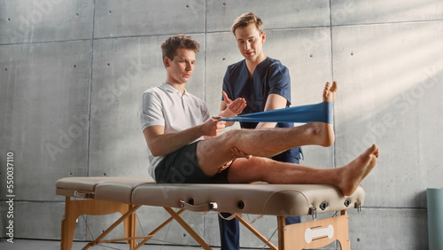 Fotografía Sport Physiotherapy Specialist Showing How to Stretch a Rubber Band on Specific Muscle Groups or Joints to Young Male Athlete