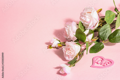 Blooming roses on a branch, a heart with the word "Love". Valentines Day or Wedding concept