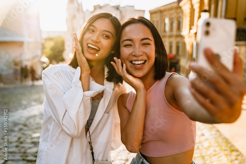 Foto Two young beautiful smiling happy asian girls taking selfie