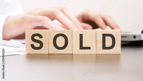 man made word SOLD with wood blocks on the background of the office table. selective focus. business concept.