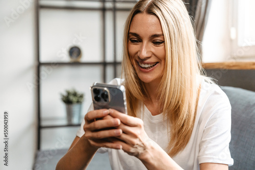 Blonde white woman using mobile phone while resting at home