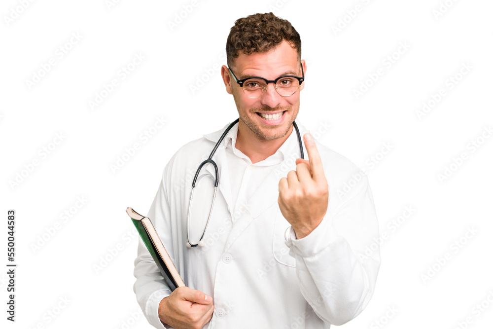 Young doctor caucasian man holding a book isolated pointing with finger at you as if inviting come closer. Young doctor caucasian man holding a book isolated pointing with finger at you as if inviting come closer.