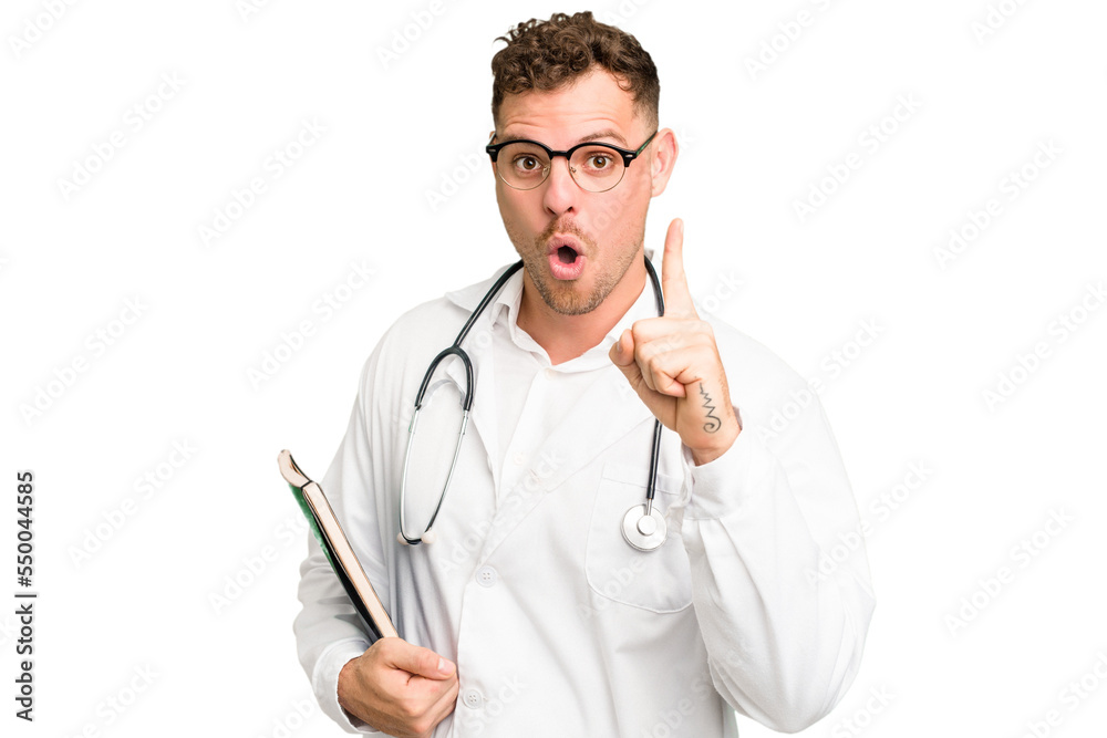 Young doctor caucasian man holding a book isolated having an idea, inspiration concept. Young doctor caucasian man holding a book isolated having an idea, inspiration concept.