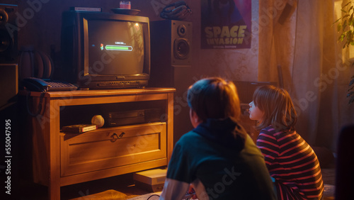 Nostalgic Childhood Concept: Young Boy and Girl Playing Old-School Arcade Video Game on a Retro TV Set at Home in a Room with Period-Correct Interior. Kids Waiting For Level to Load.