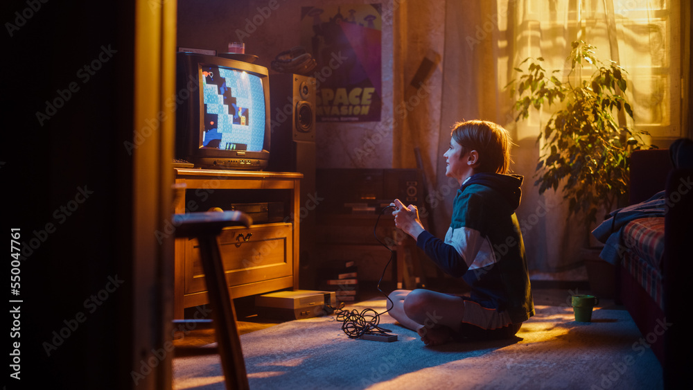 Young Boy Playing Eighties Eight Bit Arcade Video Game on a Gaming Console at Home in His Room with Old-School Interior. Child Successfully Wins the Level. Nostalgic Childhood Concept.
