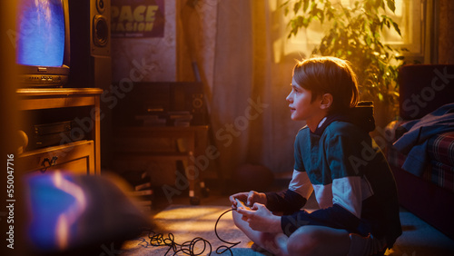 Young Boy Playing Eighties 2D Arcade Space Shooter Video Game on a Gaming Console at Home in His Room with Old-School Interior. Child Successfully Wins the Level. Nostalgic Retro Childhood Concept.