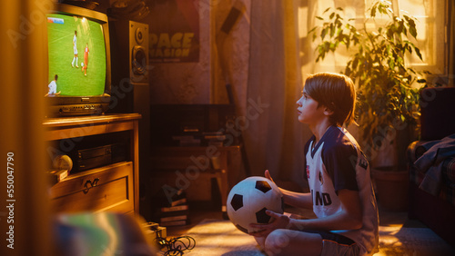 Young Sports Fan Watches a Soccer Match on TV at Home. Curious Boy Supporting His Favorite Football Team, Feeling Proud When Players Score a Goal. Nostalgic and Retro Childhood Concept. photo