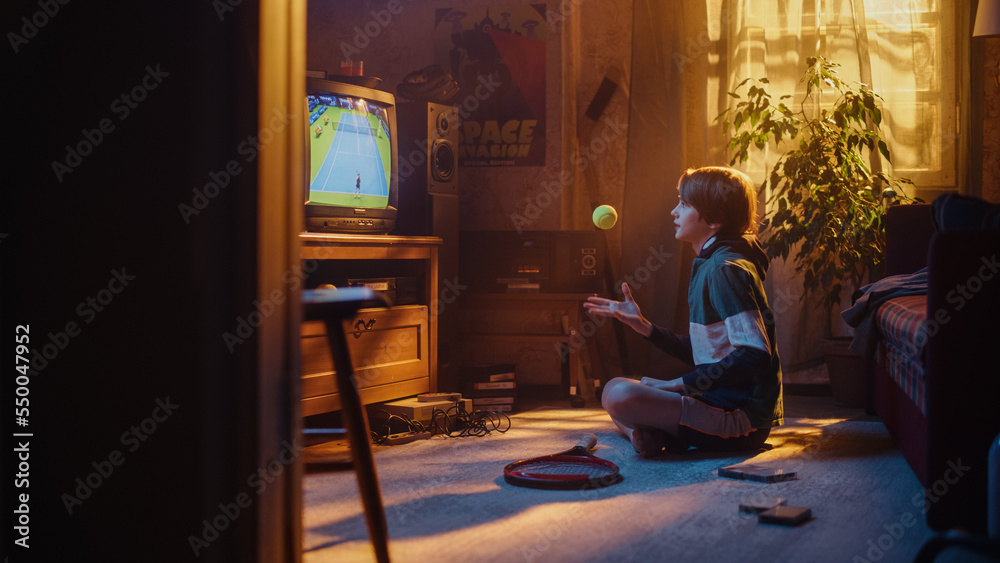 Young Sports Fan Watches a Tennis Match on TV at Home. Handsome Boy Supporting His Favorite Player, Nervously Holding a Green Tennis Ball. Nostalgic Retro Childhood Concept.
