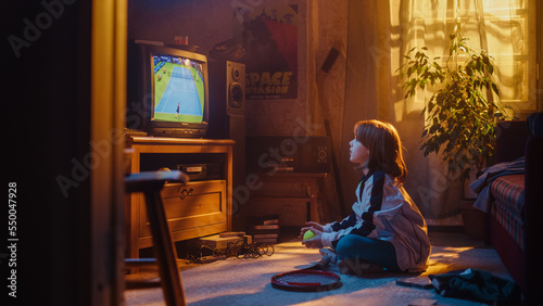 Nostalgic Retro Childhood Concept. Young Girl Watches a Tennis Match on TV in Her Room with Dated Interior. Supporting Her Favorite Player  Getting Excited While Watching an Important Game.