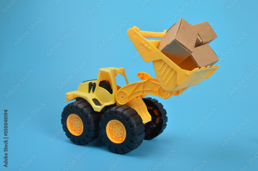 Yellow backhoe with paper boxes isolated on a blue background. Yellow backhoe with paper boxes isolated on a blue background.