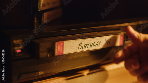 Quadro su tela Close Up of a Person Inserting a VHS Cassette in a Player with Nostalgic Birthday Footage from Home Video Camera