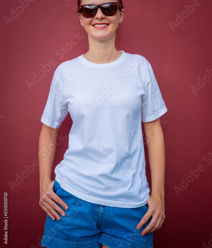 Female model wearing white blank t-shirt on the background of an burgundy wall.