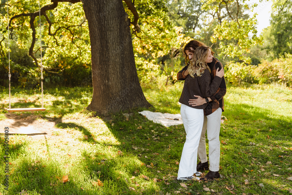 Young loving couple hugging while standing in park Young loving couple hugging while standing in park
