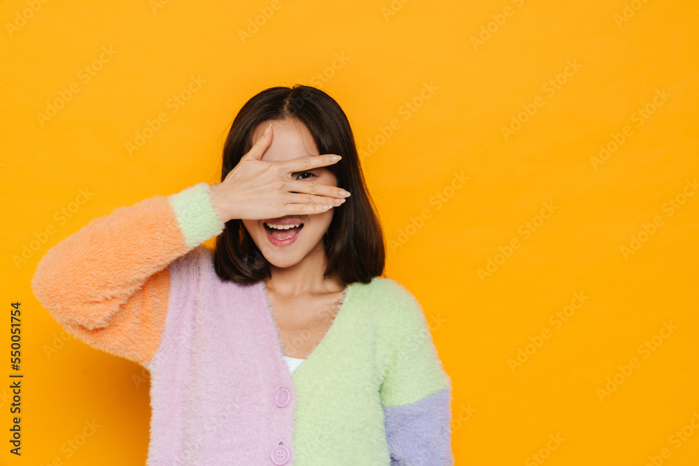 Asian young woman wearing sweater laughing while covering her eyes Asian young woman wearing sweater laughing while covering her eyes