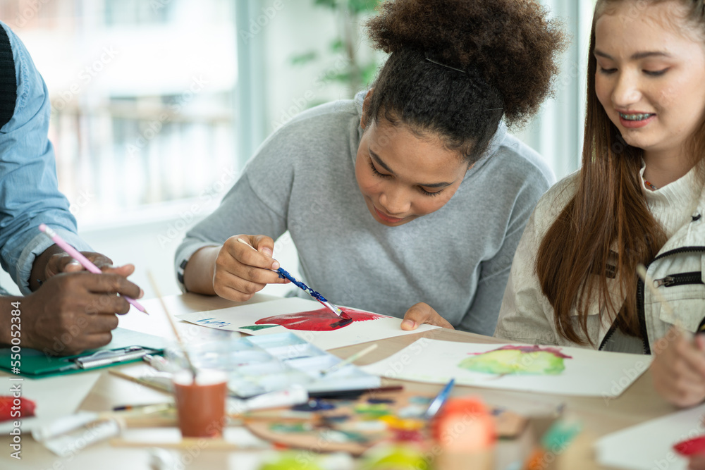 © winnievinzence - Group of diversity students enjoy drawing and painting in arts class with friends. happy smiling kids using paintbrush sketching on paper. support creative skill in a classroom at school.