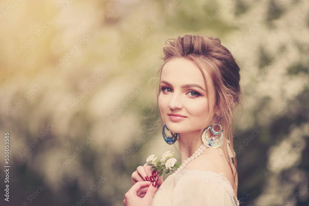 Beautiful fair-haired girl in a spring park near a lush bush of spirea, which is called the Beautiful fair-haired girl in a spring park near a lush bush of spirea, which is called the