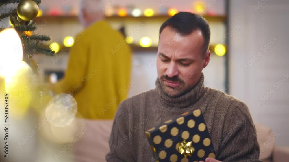 Disappointed man opens gift box on Christmas eve. Realtime