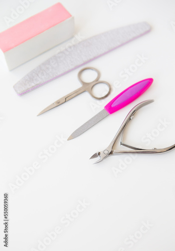 Professional manicure set on a white table. The concept of hand care, salon procedures. File, scissors, buff, bamboo stick, cuticle nippers.