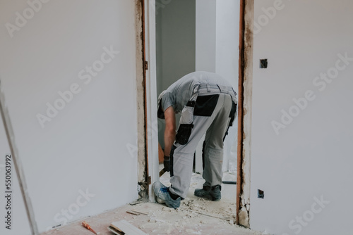 A man working with a crowbar in a doorway.