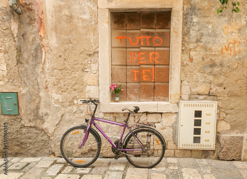 An old bicycle, an old stone street, a window closed with wooden shutters with the inscription Everything for You. Street in Croatia.