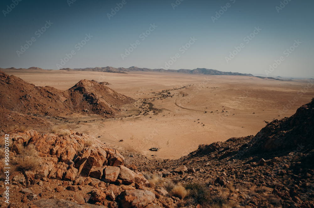 Blick von einem Gipfel am Rande der Aus-Berge in die Weite der Namib - unmittelbar unterhalb des Gipfels ist im Tal ein Haus zu erkennen, Klein-Aus Vista, Namibia