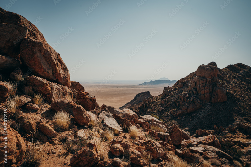 Blick entlang mehrerer Felsen am Rande der Aus-Berge in die Weite der Namib, Klein-Aus Vista, Namibia