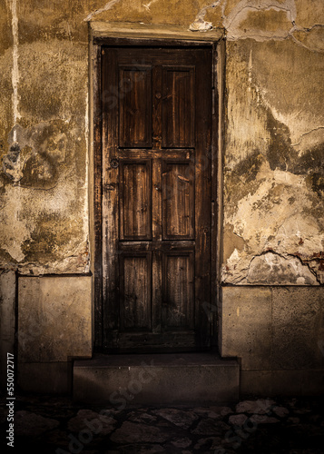 stare brązowe drewniane drzwi w starym zniszczonym budynku w nocy po zmroku