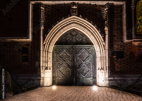 stara zdobiona brama spiżowa kościoła w nocnym oświetleniu