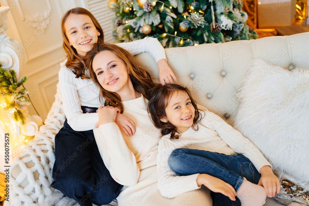 mother and daughters on the couch by the Christmas tree. mother and daughters on the couch by the Christmas tree.