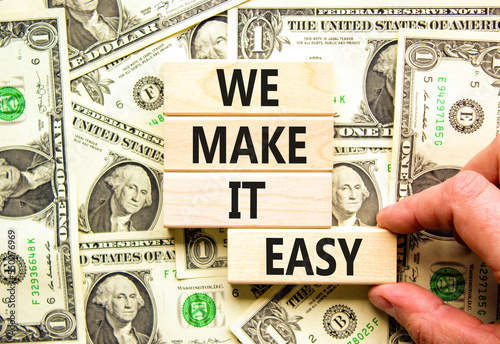 We make it easy symbol. Concept words We make it easy on wooden cubes. Beautiful background from dollar bills. Businessman hand. Business motivational we make it easy concept. Copy space.