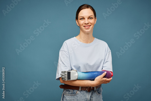 Studio portrait of positive young woman with bionic arm photo