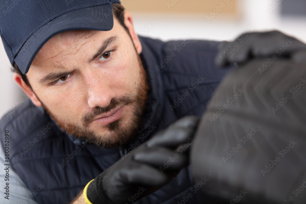 young car mechanic inspecting tyre
