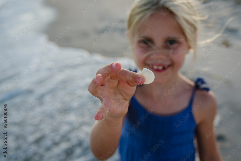 High angle portrait of girl showing seashell while standing at Tobay Beach High angle portrait of girl showing seashell while standing at Tobay Beach