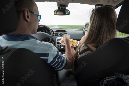 Rear view of couple eating French fries in car photo