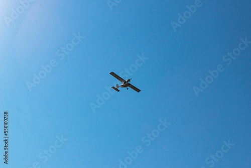 Low angle view of silhouette unmanned aerial vehicle flying against clear blue sky during sunny day