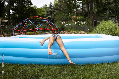 young girl feeling water in blowup pool on summer day photo