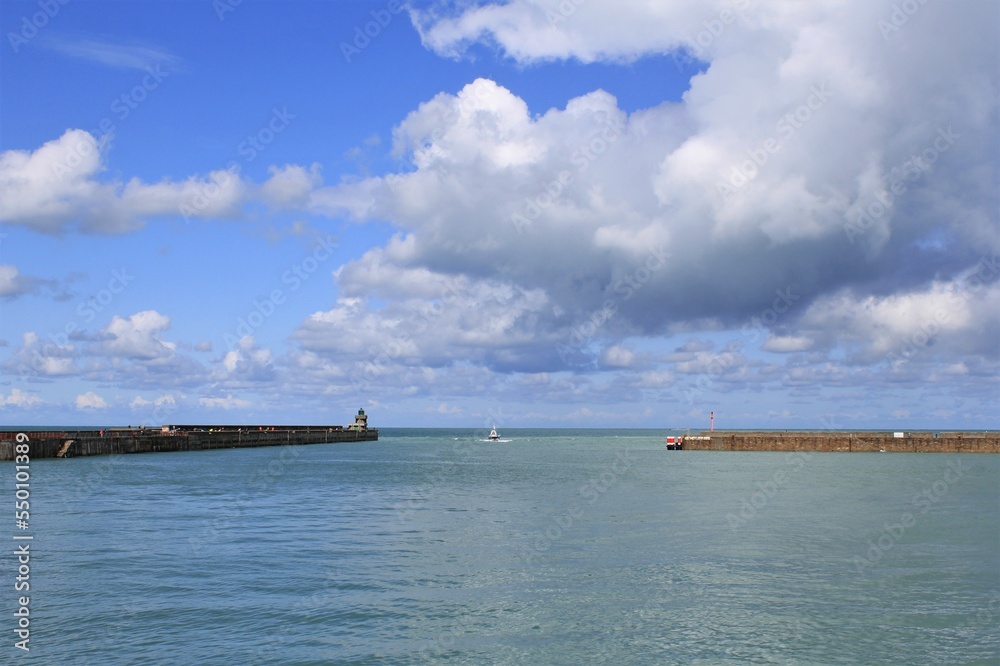 beautiful french seascape in Dieppe with the long pier at the entrance of the harbour and a blue sky with white clouds