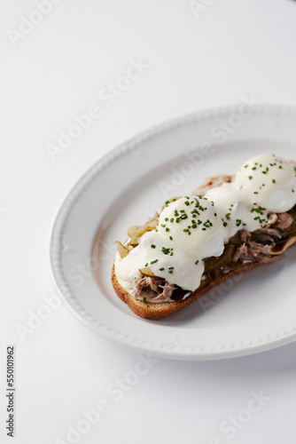 sandwich with poached egg and stew, drizzled with cheese and herbs