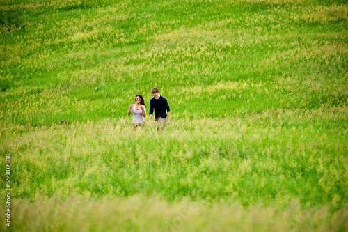 Young couple walking on a grass trail through a bright green field at Spirit Mound, South Dakota. photo