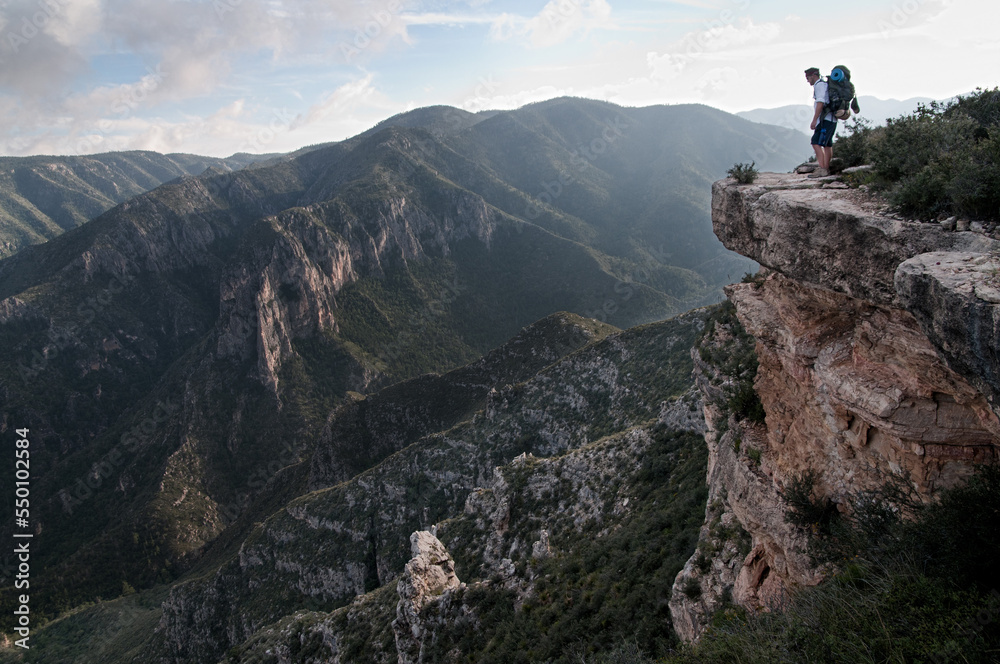 A backpacker peers over a ledge into McKittrick Canyon at Guadalupe National Park. A backpacker peers over a ledge into McKittrick Canyon at Guadalupe National Park.