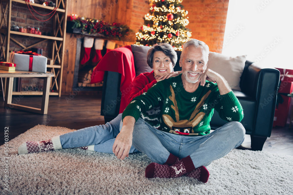 Obraz premium Full body portrait of two cheerful satisfied aged people sit carpet floor cuddle fairy christmastime miracle indoors