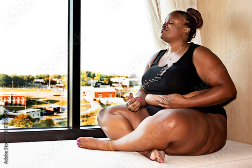 Black woman with braids meditating in front of window